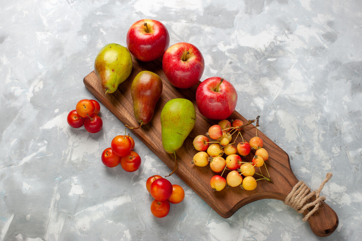 李子在浅白的桌子上俯瞰新鲜的红苹果和甜樱桃 李子和梨红色食物苹果