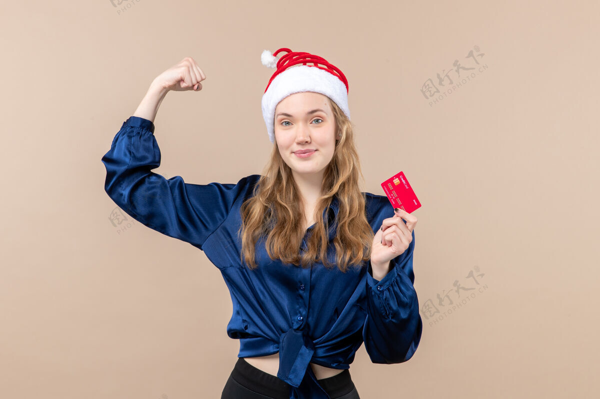 钱正面图年轻女性手持红色银行卡上粉色背景的圣诞钱照片新年感慨年轻情感圣诞节