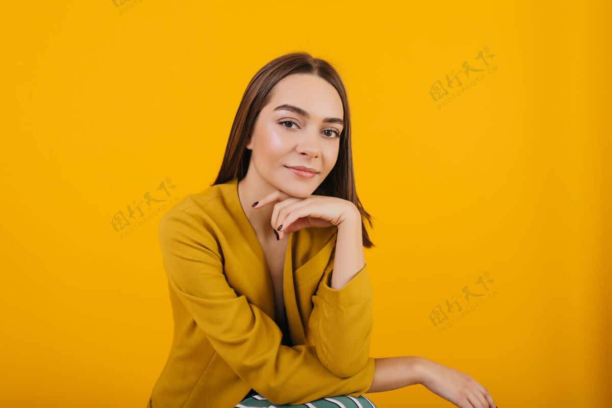 有趣穿着时髦的黄色夹克的女模特摆姿势室内一张令人高兴的深色头发女人摆姿势的照片室内可爱明亮