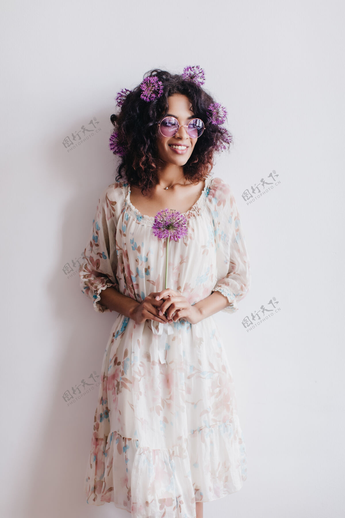 美丽美丽的黑人女模特手持鲜花站在白墙前快乐的非洲女士手持紫色的葱发型模特时尚
