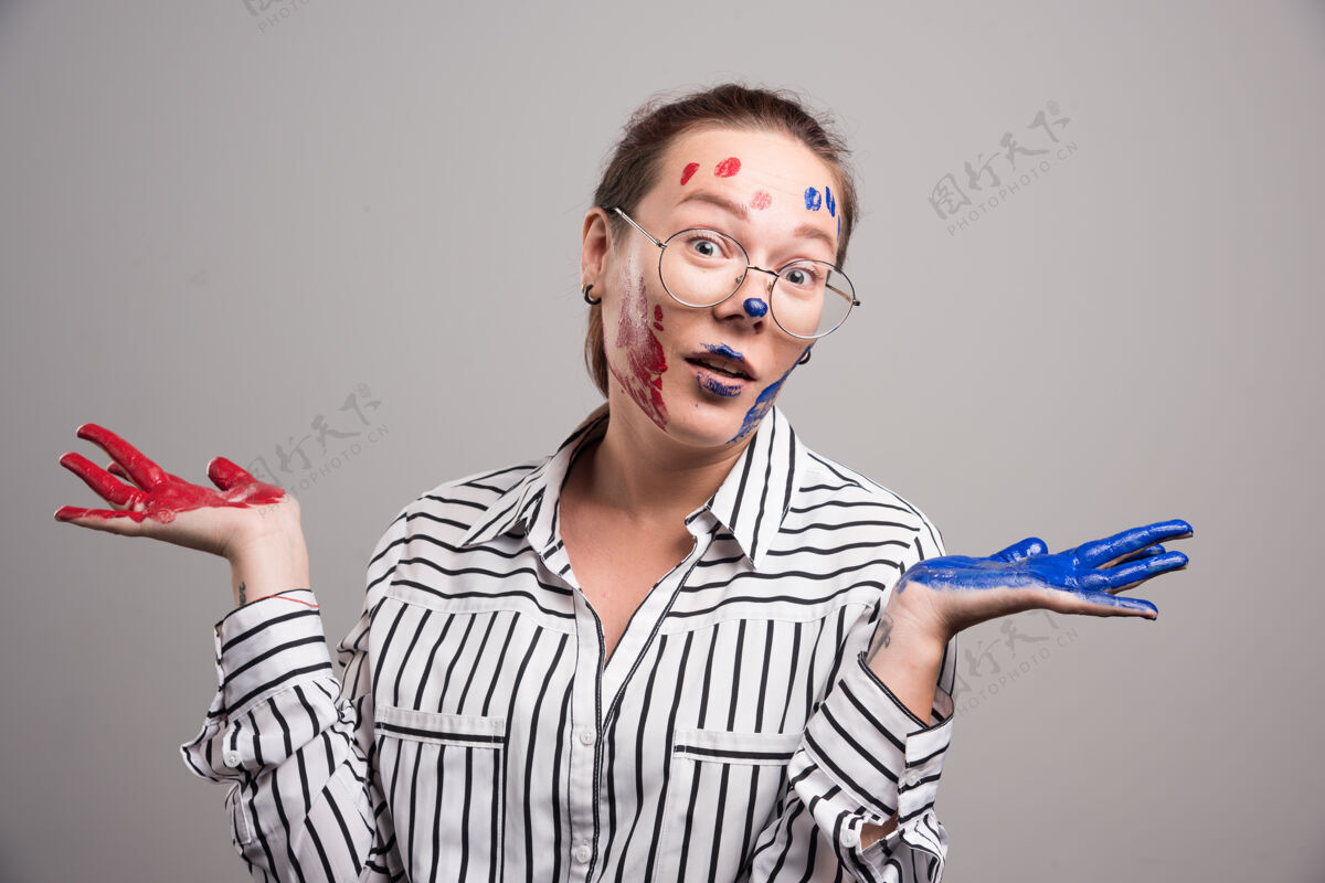手在灰色背景上 一个女人在脸上摆着颜料高质量的照片眼镜画明亮