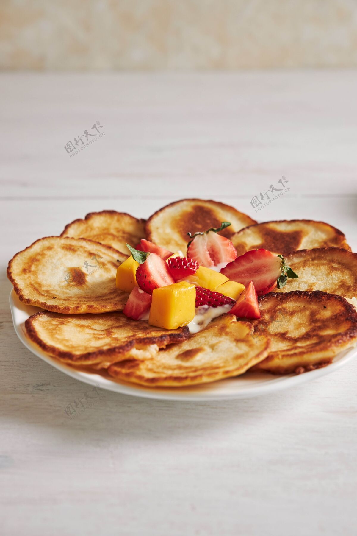 自制白木桌上美味的水果煎饼的垂直镜头餐美味盘子