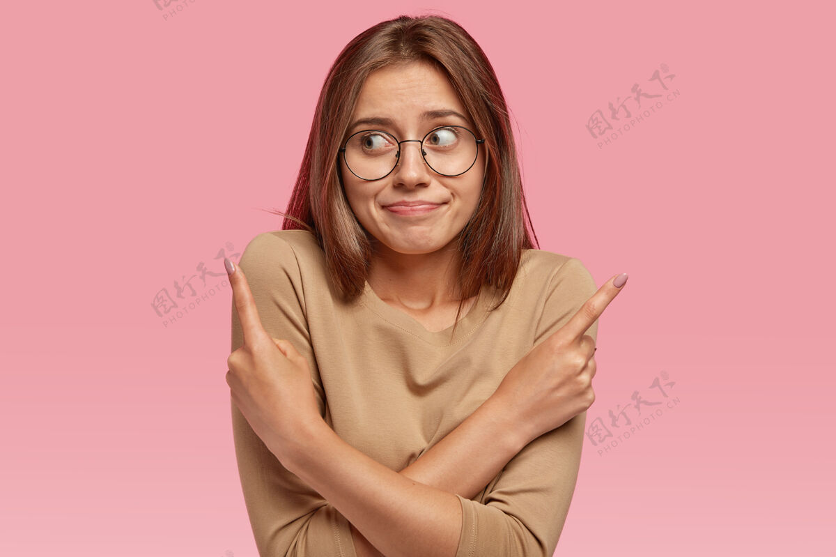 食指容貌可人的女人在两个选择之间犹豫 指向不同的侧面 双手交叉在胸前 表情混乱指示悲伤眼镜