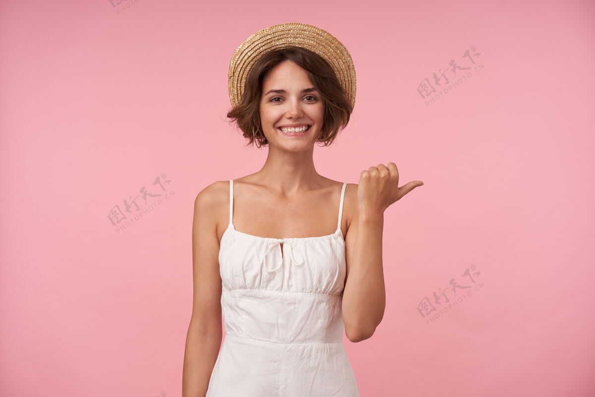 黑发快乐美丽的年轻黑发女子 随意的发型 一边竖起大拇指一边看着快乐 穿着白色优雅的连衣裙和船夫帽 与世隔绝美丽情绪姿势