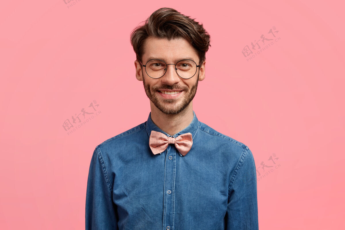 衬衫照片中的帅哥笑容可掬 发型新潮 神采奕奕 身着时尚喜庆的服装 站在粉色的墙上酷胡须胡茬