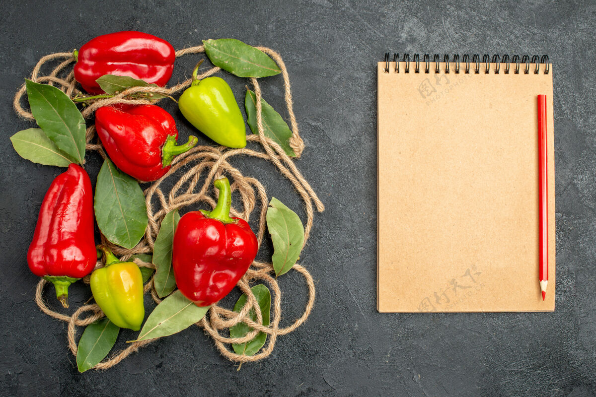 西红柿顶视图明亮的辣椒与月桂叶旁边的笔记本红笔灰色背景与自由空间胡椒健康胡椒