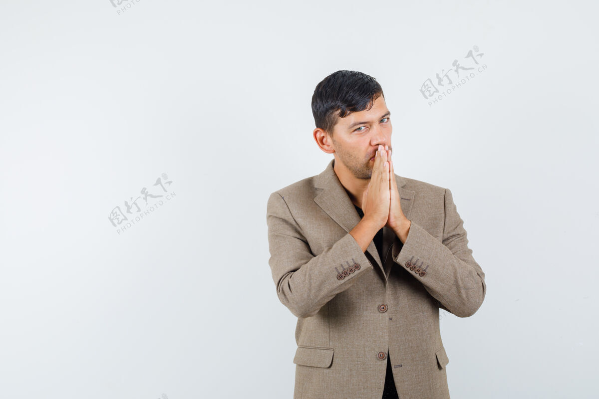 休闲身穿灰褐色夹克的年轻男性 表现出祈祷的姿态 看上去很平静 正面视图表情灰色时尚