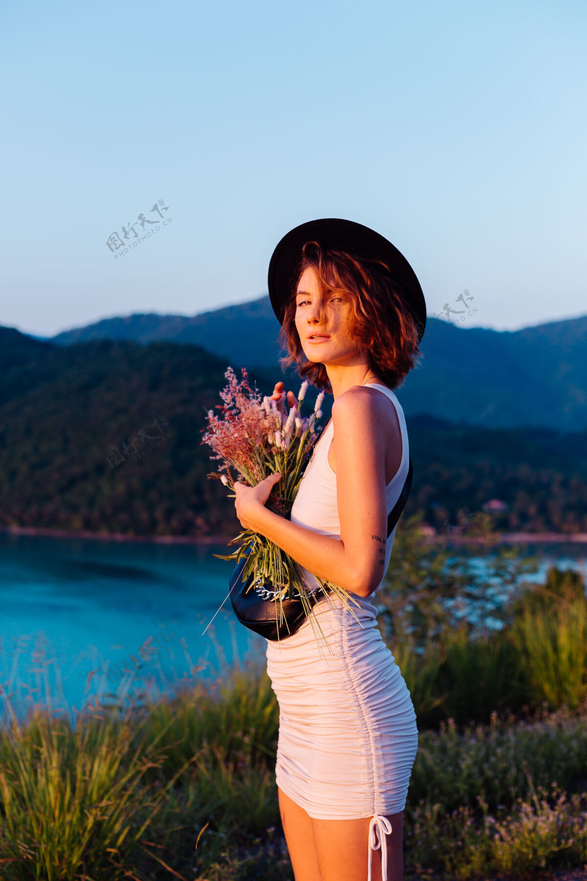 日落穿着夏装的年轻白种女人的浪漫写真 在山上的公园里享受着令人惊叹的热带海景欢乐优雅异国情调
