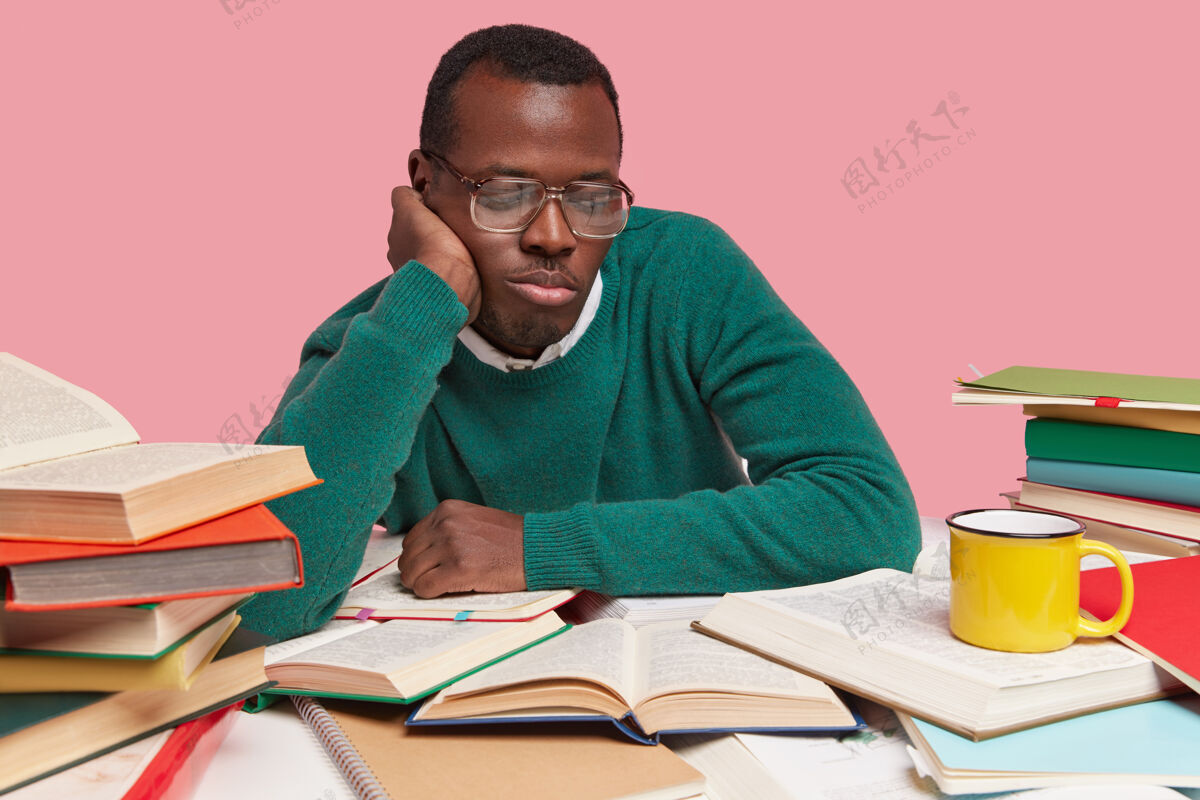 时髦人士照片中的黑人全神贯注地在翻开的书中专心看书 穿着绿色的套头衫 寻找新的信息个人书呆子老师