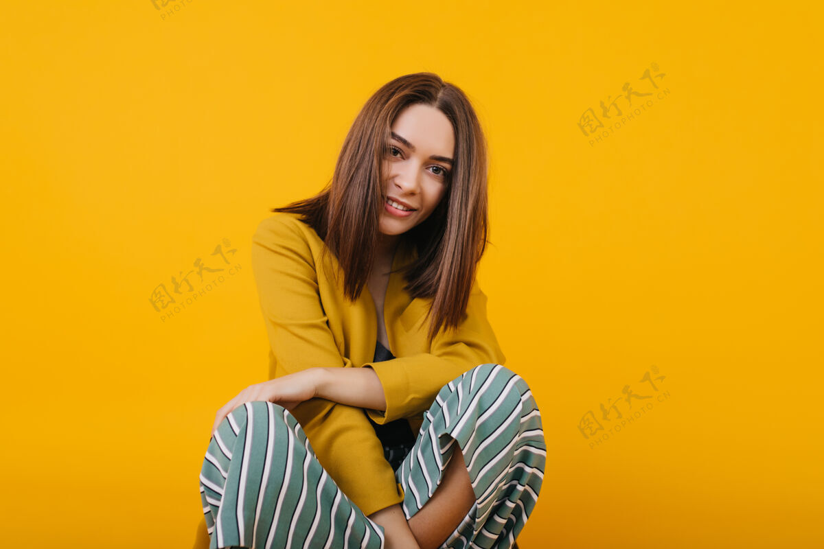 休息迷人的棕色眼睛的高加索女孩坐着照片上的无忧无虑的女子直发摆姿势黄色优雅模特