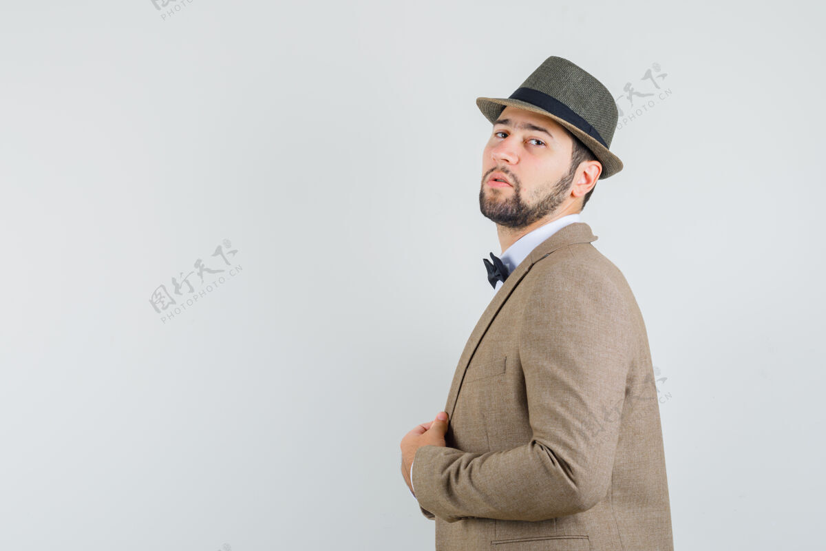 抱着一个穿着西装 戴着帽子拿着夹克的年轻人 看上去很自信手肖像夹克