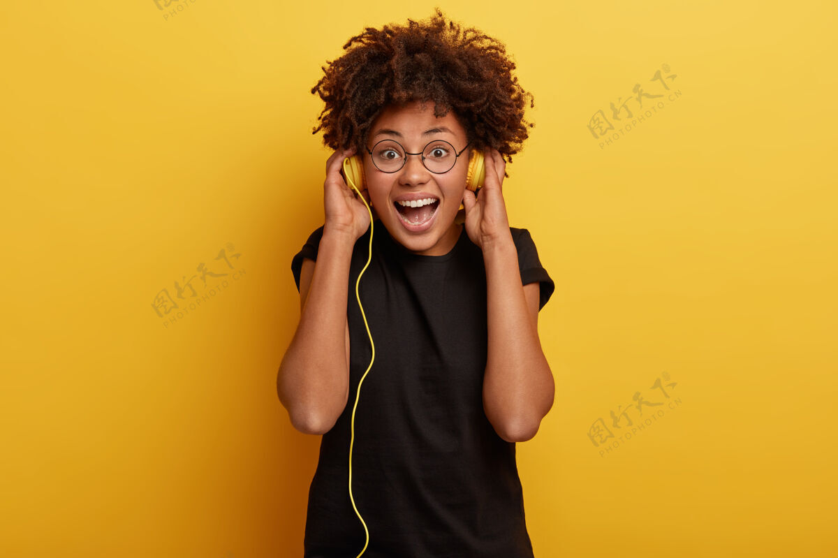 情感可爱的黑皮肤女人和非洲发型的照片从音乐中得到灵感 挑选好的轨道乐观愉悦人类