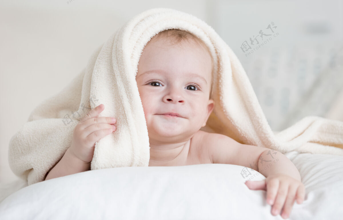 裸体可爱的男婴躺在床上的白色毯子下的画像毯子谎言毛巾